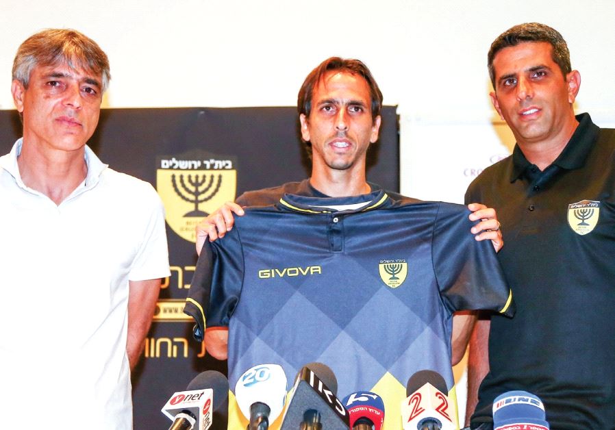 New Beitar Jerusalem midfielder Yossi Benayoun (center) poses with the team’s shirt alongside head c