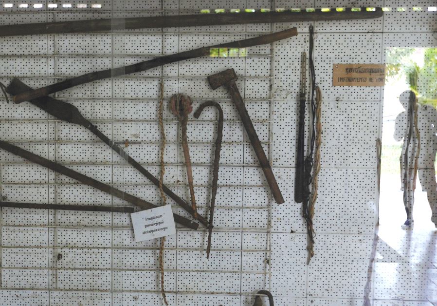 A VISITOR is reflected in a showcase with torture instruments at Tuol Sleng Genocide Museum in Phnom
