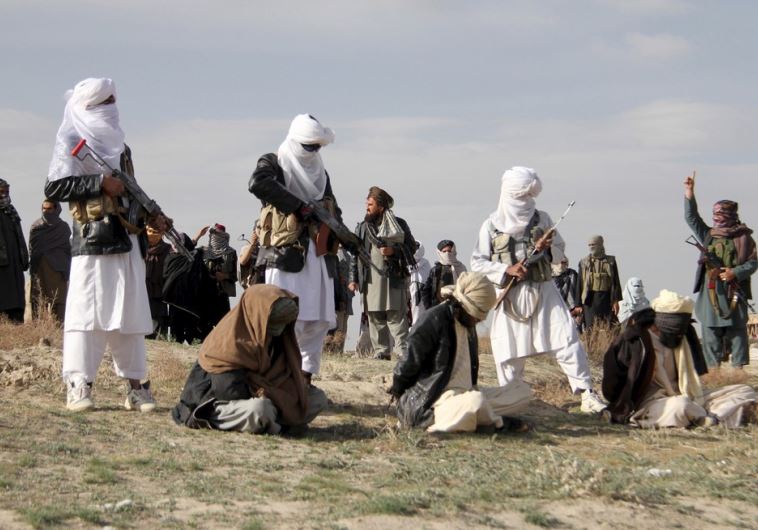Taliban insurgents stand over three men before executing them