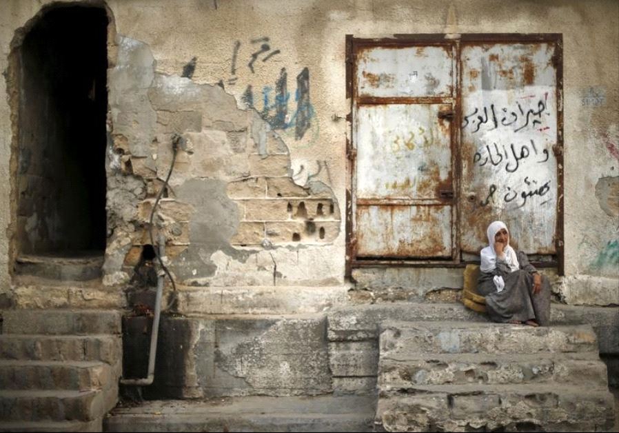 A Palestinian woman sits outside her house as she escapes the heat during a power cut at Shatti (bea