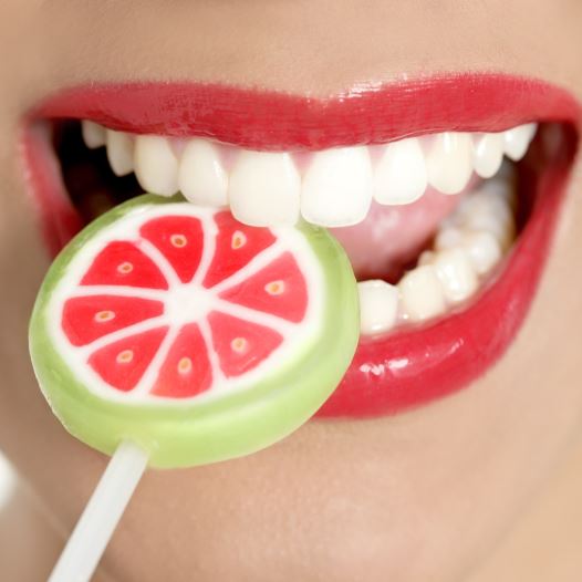 A woman with perfect teeth chews on a lollipop