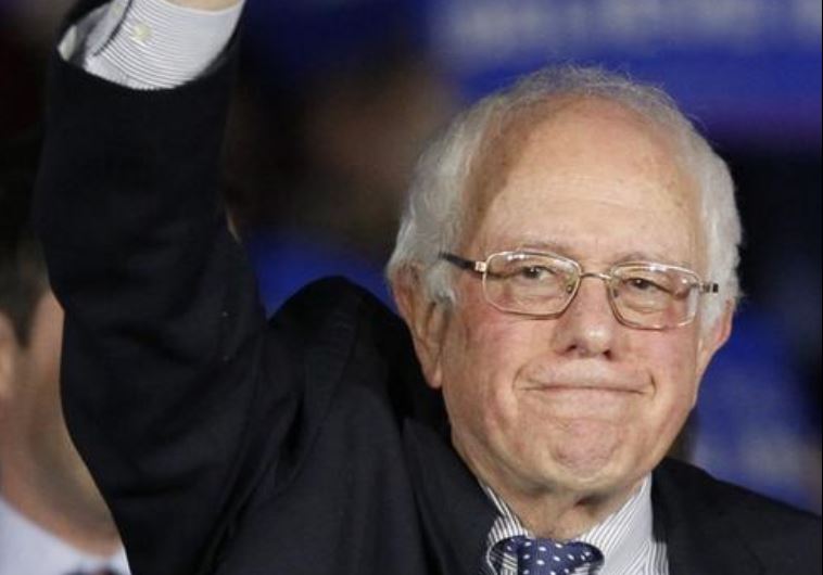 US Democratic presidential candidate Bernie Sanders raises a fist as he speaks at his caucus night r