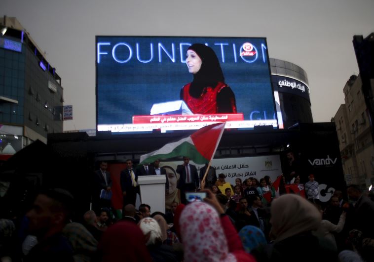 Palestinians watch on a screen in the West Bank city of Ramallah March 13, 2016 as primary school te