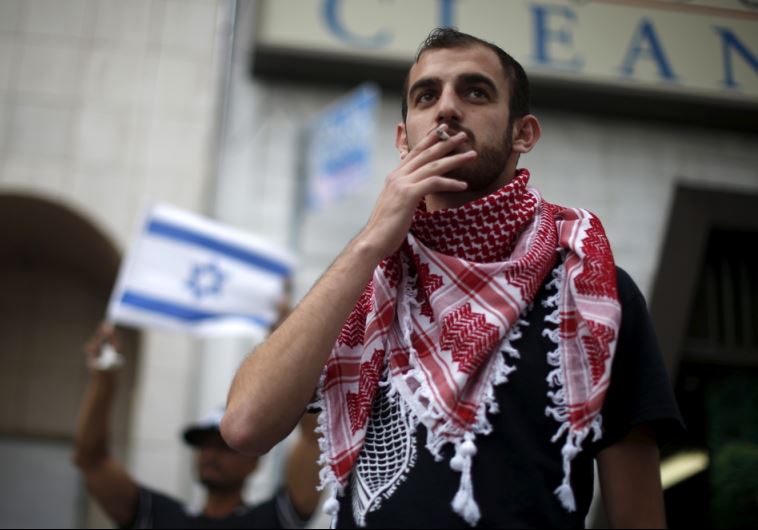 A Palestinian protester stands next to an Israeli counter-protest during a demonstration in LA