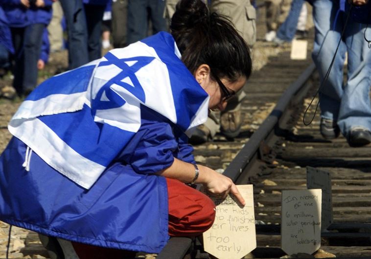A Jewish girl places a wooden board on railway tracks to commemorate her killed relatives