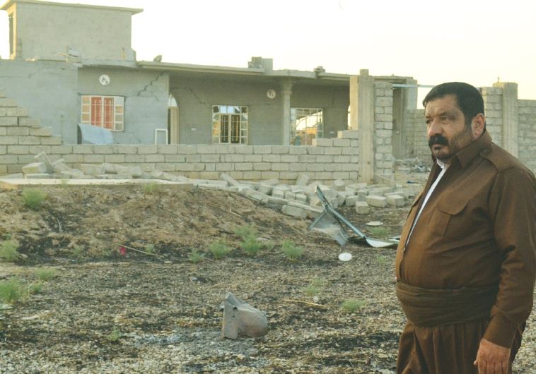 A KAKAI PESHMERGA volunteer stands next to a house destroyed by Islamic State. His brother was kille