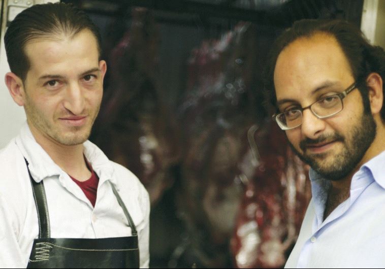 FADI KATTAN (right) makes a purchase from his butcher last week for his Hosh al-Syrian guest house i