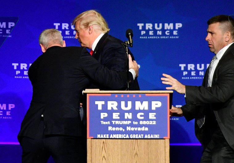 US Republican presidential nominee Donald Trump is hustled off the stage by security agents after a 