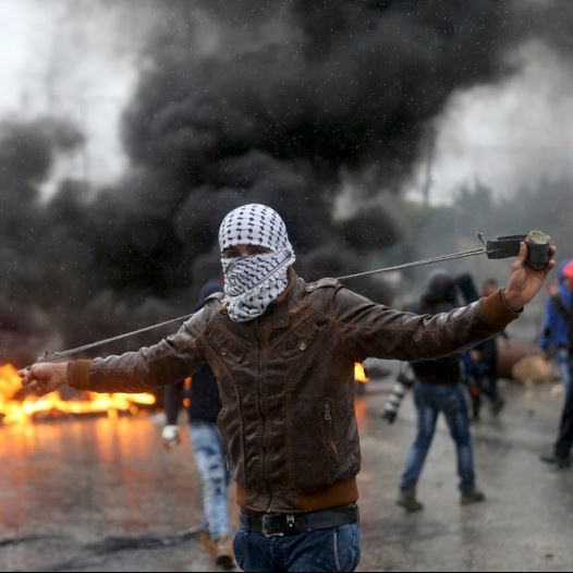 A Palestinian protester prepares his sling to hurl stones towards Israeli troops 