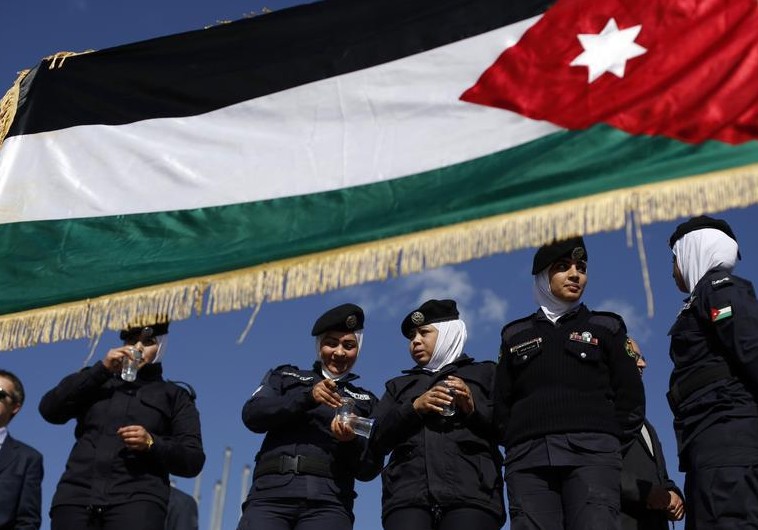 Jordanian police women stand guard near a Jordanian national flag during a pro-monarchy rally