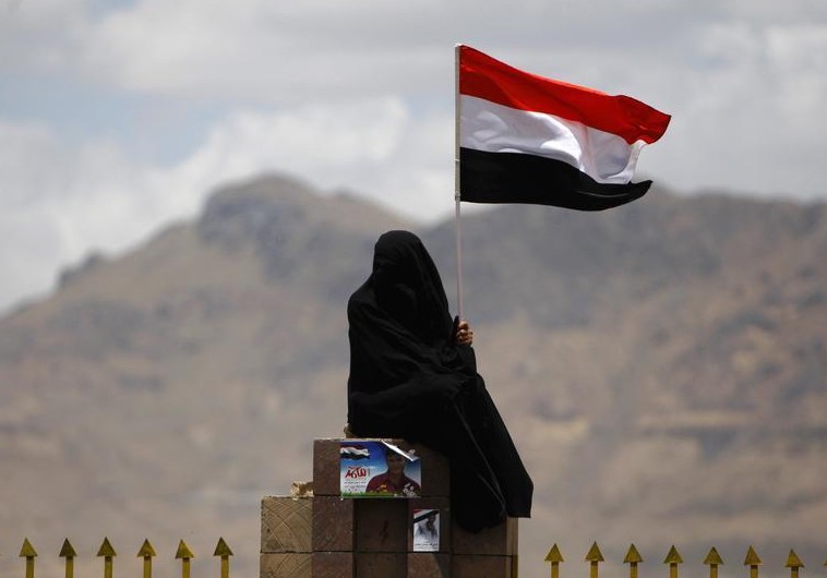 A woman holds the Yemenite national flag