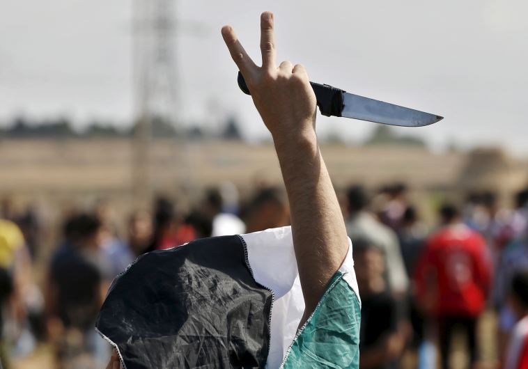 A masked Palestinian protester holds a knife during a protest in Gaza
