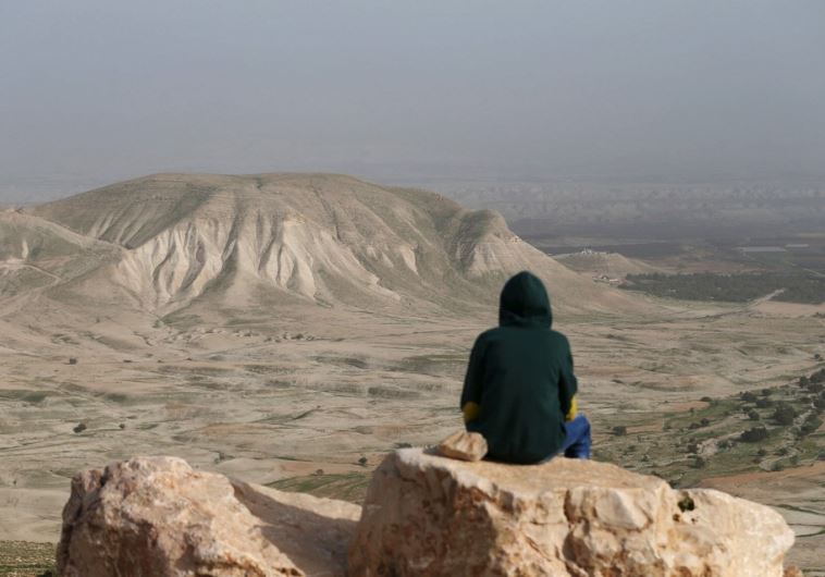A Palestinian man sits on a rock at Jordan Valley near the West Bank city of Jericho