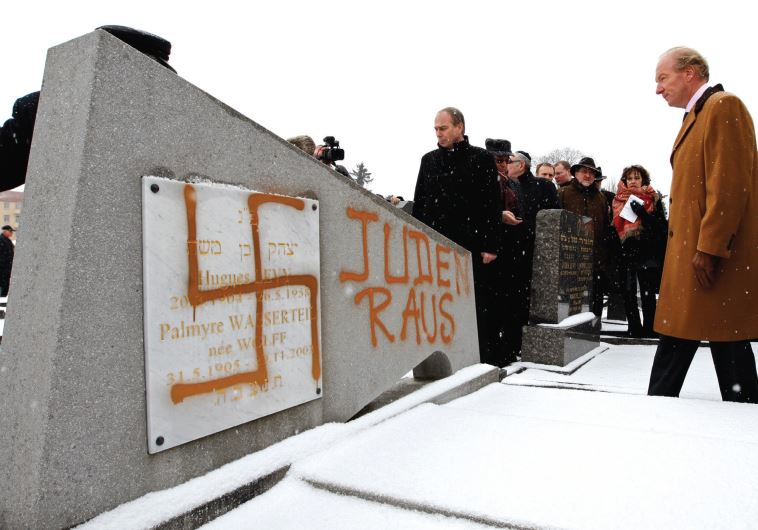 FRANCE’S THEN interior minister Brice Hortefeux walks next to a tombstone desecrated by vandals with
