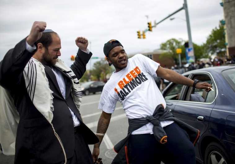 People react as police line up at North Ave and Pennsylvania Ave in Baltimore