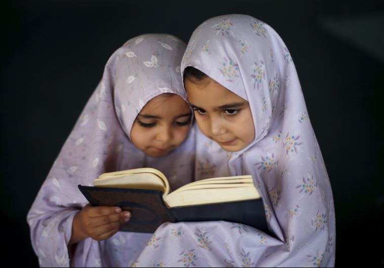 Palestinian girls read the Koran as they attend a Koran memorization lesson during summer vacation