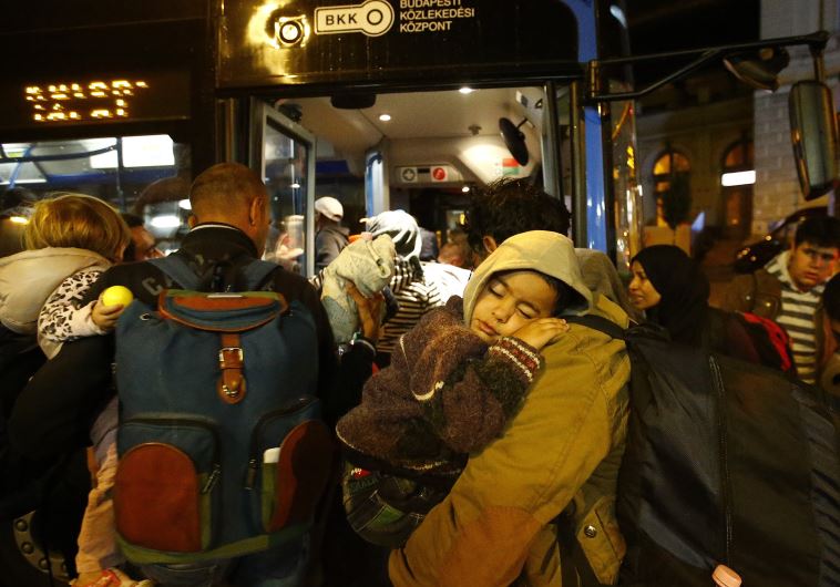 Migrants enter bus, which is supposed to leave to Austria and Germany, in Budapest, Hungary