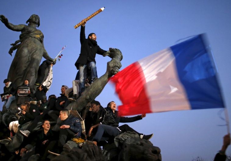 A man holds a giant pencil as he takes part in a solidarity march in the streets of Paris