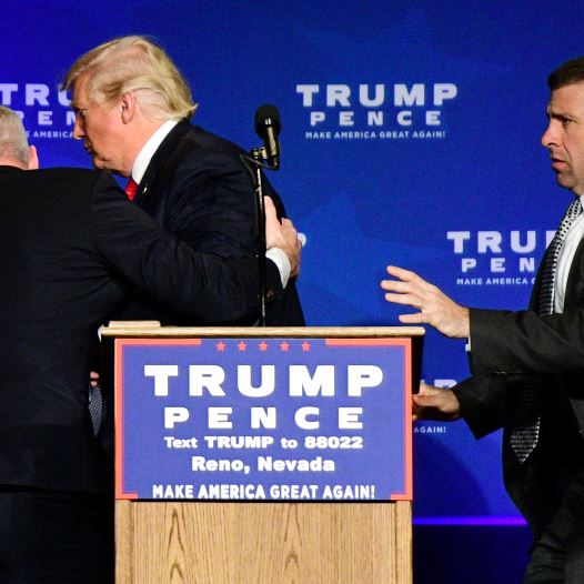 US Republican presidential nominee Donald Trump is hustled off the stage by security agents after a 