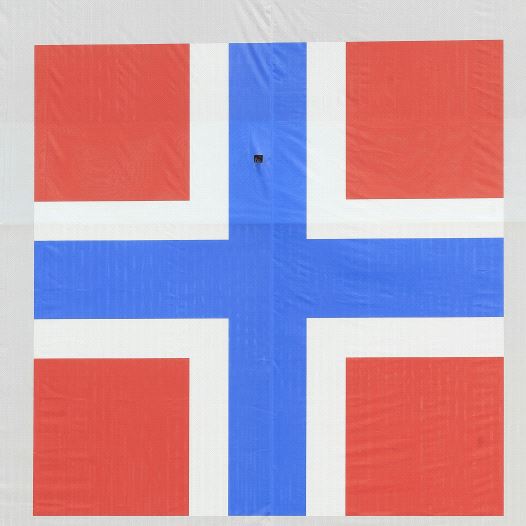 A woman cycles past a banner of the Norwegian flag attached to a warehouse in Oslo, Norway.