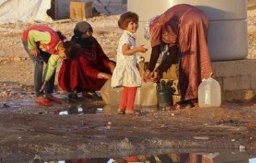 Syrian refugees collect water on  September 26, 2013. 