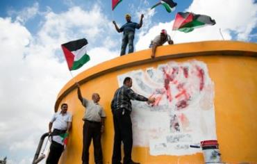 Palestinians wave flags on ruins of settlement