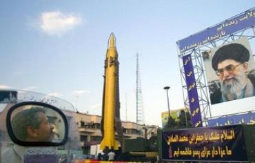 A motorcyclist looks at an Iranian-made Ghadr-F missile during a war exhibition 