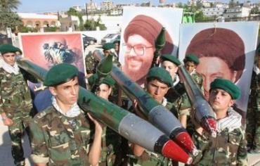 Hezbollah members carry mock rockets next to a poster of the group's leader Sayyed Hassan Nasrallah.