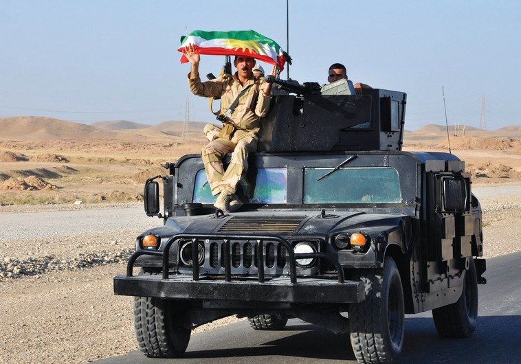 A KURDISH Peshmerga soldier holds a Kurdistan flag.