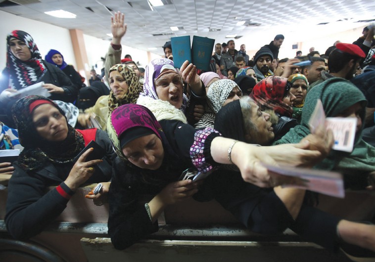 WOMEN PRESENT their passports as they ask for permits to cross from Gaza into Egypt
