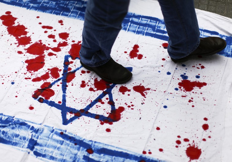 A Venezuelan student walks over a cloth with red paint and the Star of David.