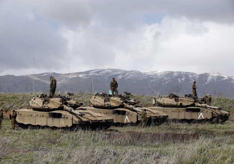 Israeli soldiers stand atop tanks in the Golan Heights near Israel's border with Syria