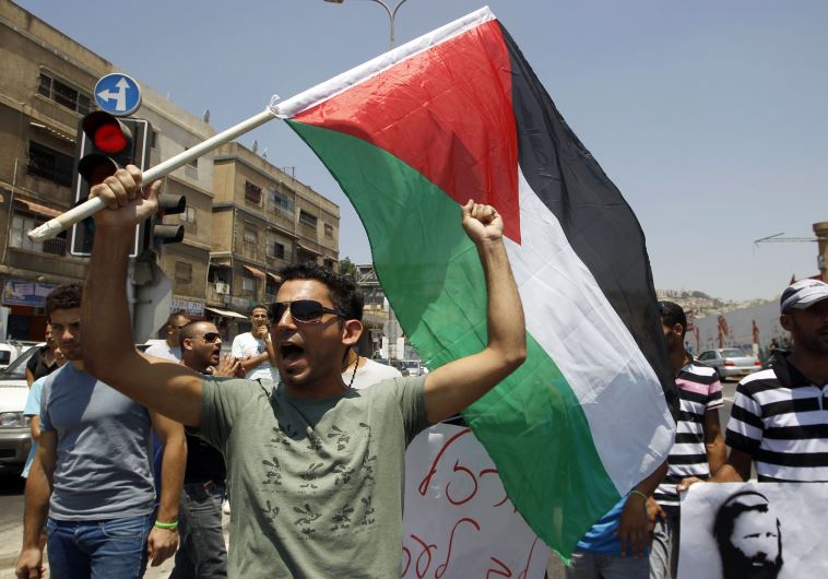 An Israeli Arab demonstrator holds a Palestinian flag during a protest in Nazareth