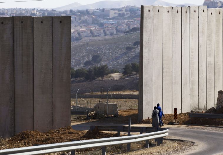 Palestinians walk near an opening in Israel's security fence east Jerusalem