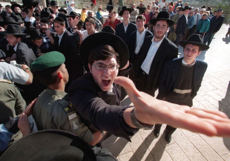 An ultra-orthodox Jew is restrained by a Border Policeman 
