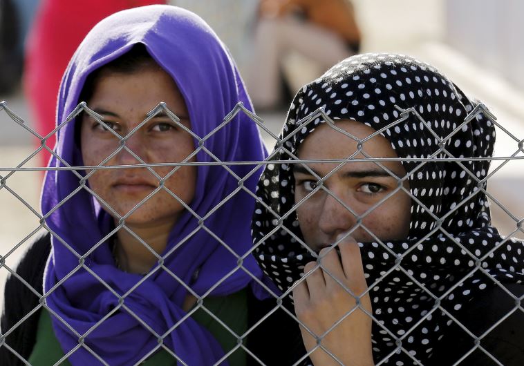 Yazidi refugees stand behind fences in the southern Turkish town of Midyat