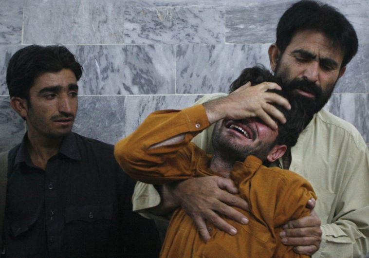 A man is comforted by his relative after he arrived at the local hospital in Quetta