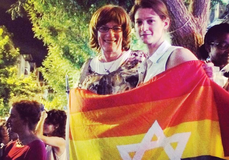 SARAH WEIL (right) and Jewish educator and trans-activist Yiscah Smith wrap themselves in a flag