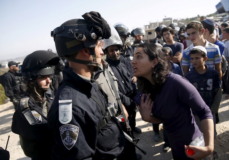 A young Jewish settler (R) speaks with an Israeli police officer 