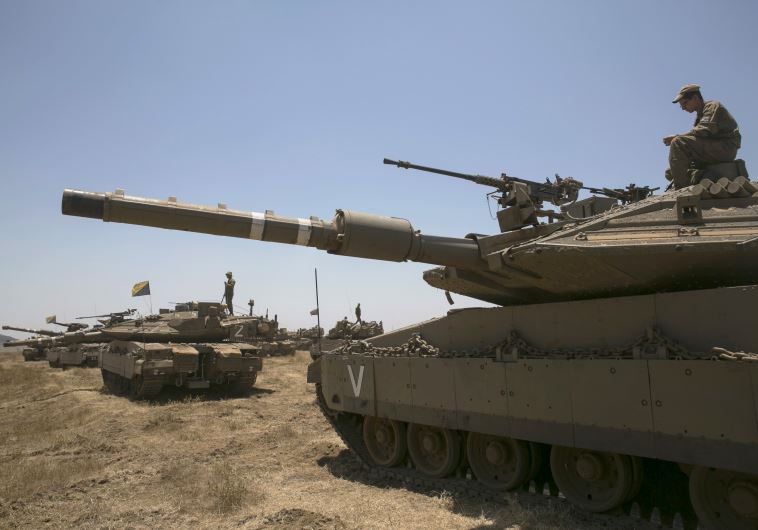 An Israeli soldier sits atop a tank during an exercise in the Golan Heights, near the ceasefire line