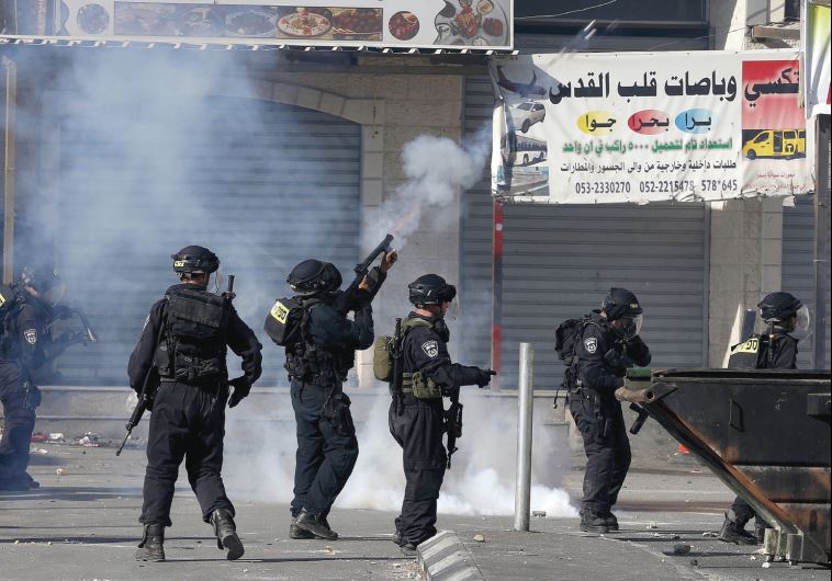 BORDER POLICEMEN fire tear gas at rock-throwers in the Shuafat refugee camp 