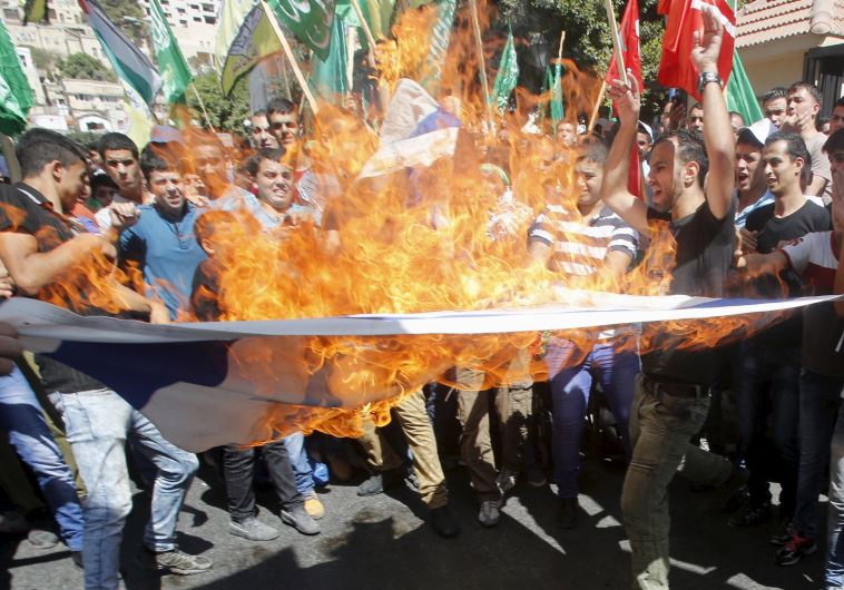 Palestinian protesters burn an Israeli flag during a protest