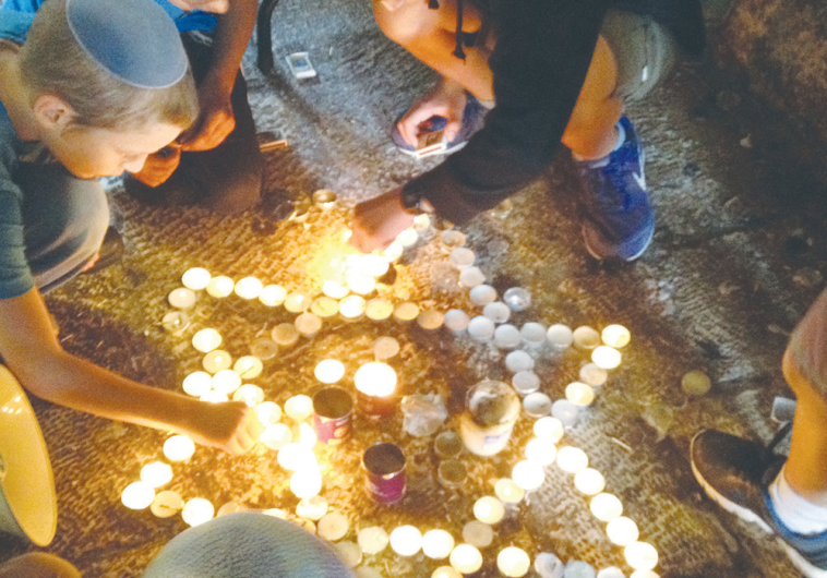 BOYS LIGHT memorial candles at the scene of two terrorist attacks