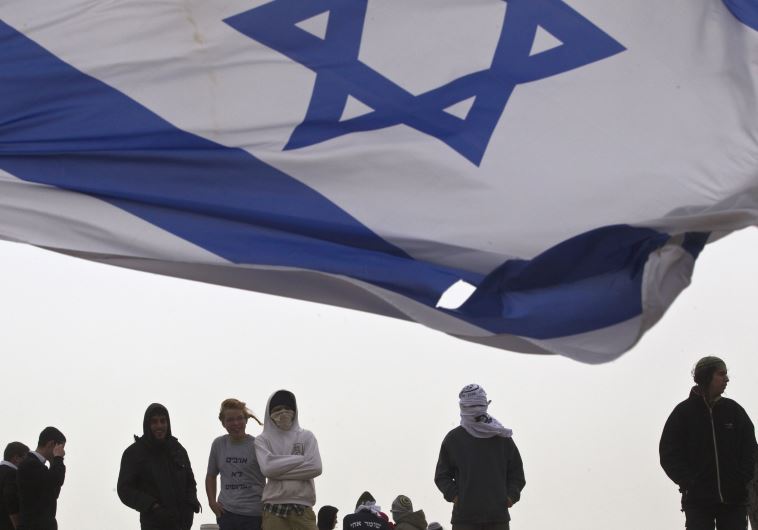 An Israeli flag flutters near Israeli youths
