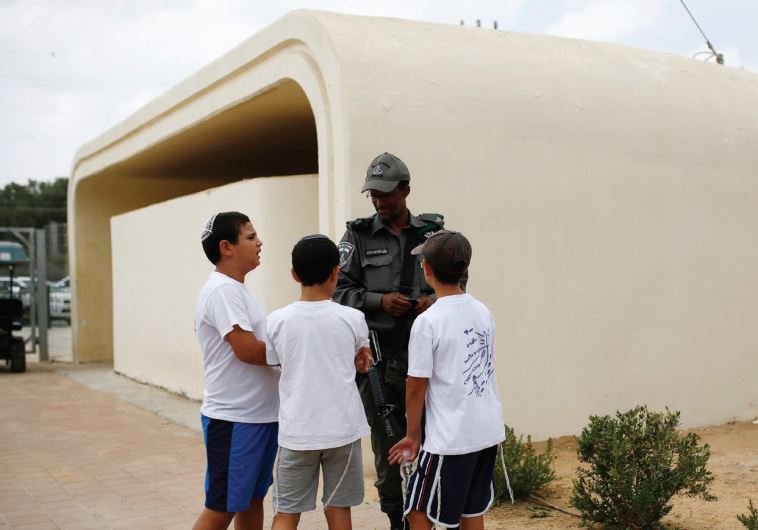 SCHOOLCHILDREN CHAT with a member of the Border Police near a bomb shelter at Kibbutz Sa’ad