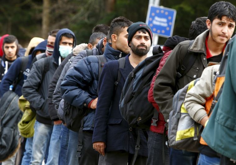 Migrants stay in a queue before passing the Austrian-German border