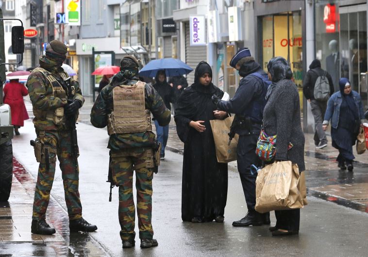 Belgian soldiers and a police officer control the documents of a woman in a shopping street in centr