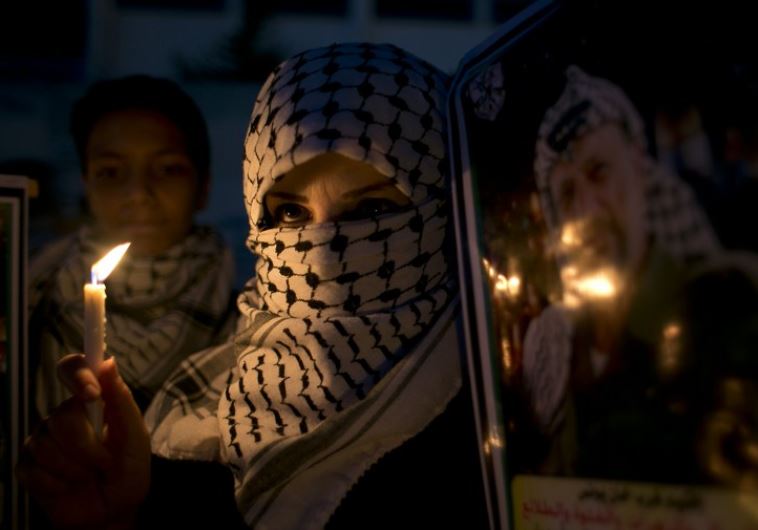 A Palestinian woman holds a candle during a protest in the southern Gaza Strip town of Khan Younis