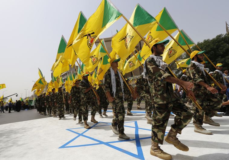 Iraqi Shi'ite Muslim men from the Iranian-backed group Kataib Hezbollah wave the party's flags