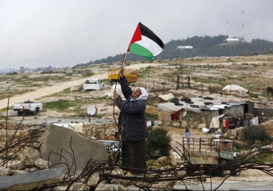 A Palestinian man hangs a Palestinian flag atop the ruins of a mosque